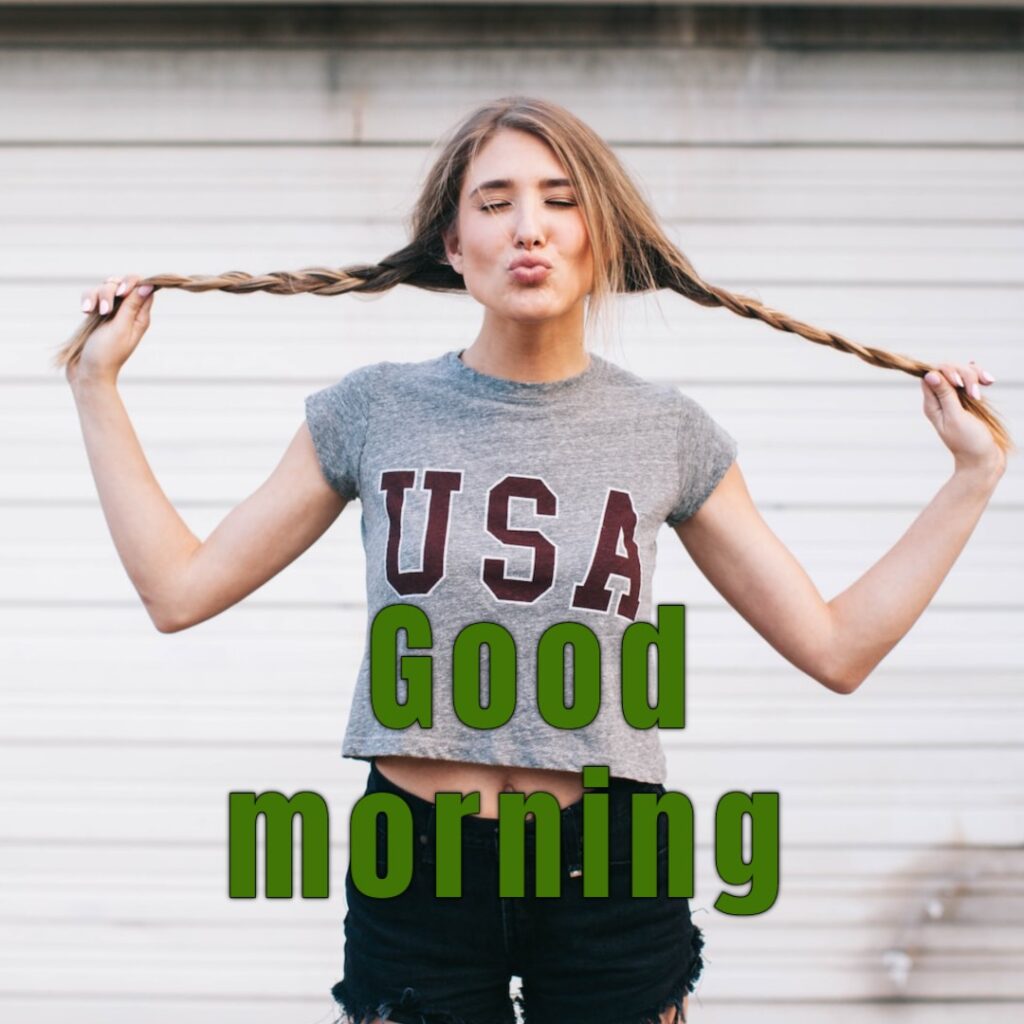 A funny girl closing eyes and stretching hair having usa t shirt looking like a funny girl good morning image
