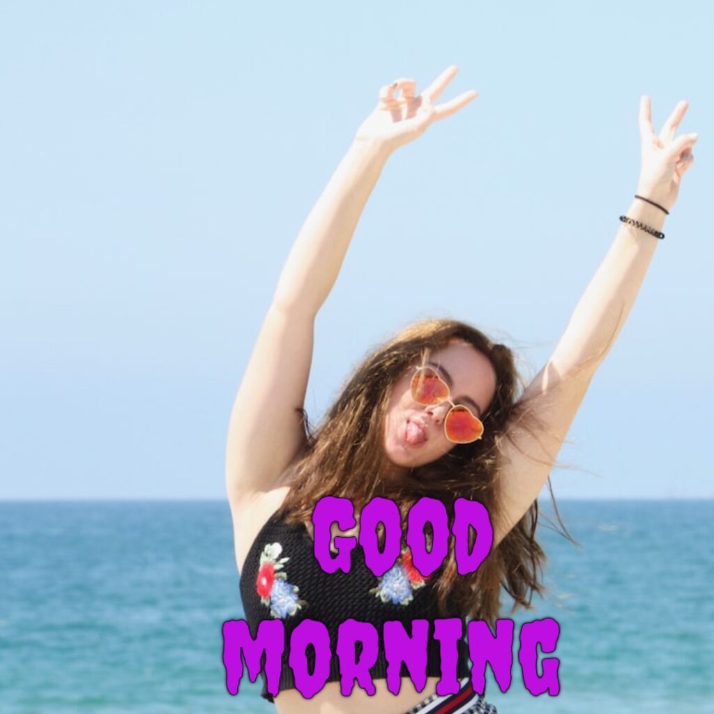 A cute funny girl in sea water having sunglasses and black blouse looking like a funny good morning image