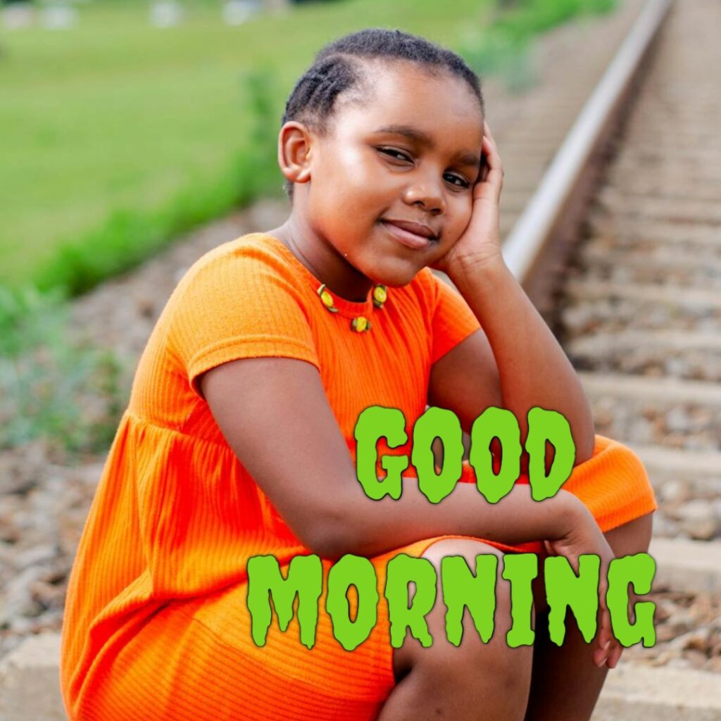 A west indies girl having orange colour frock looking like a funny girl good morning image
